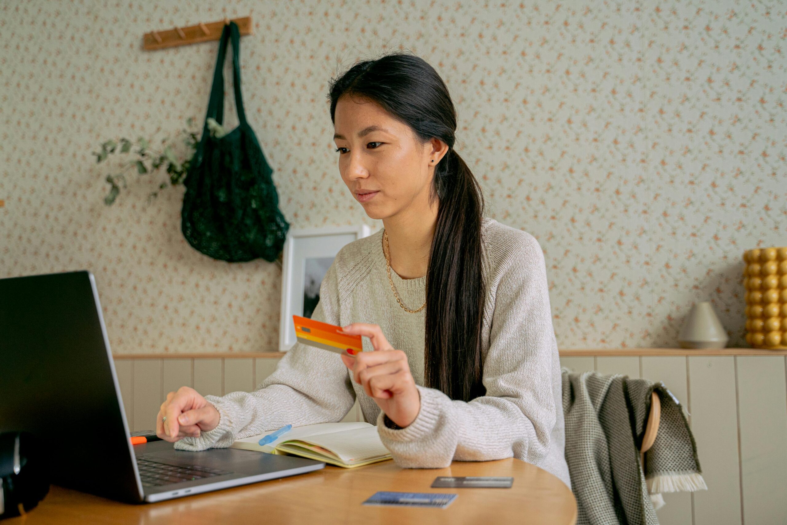 Woman Holding a Credit Card While Using a Laptop