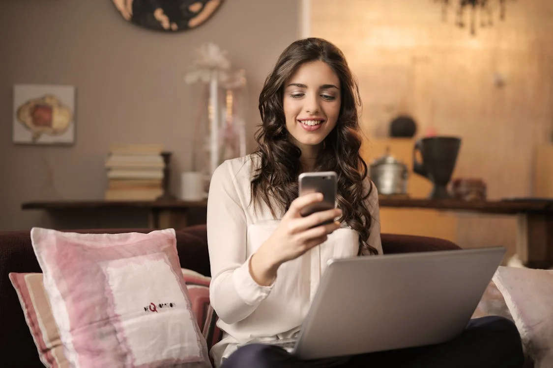 A woman using a phone and a laptop