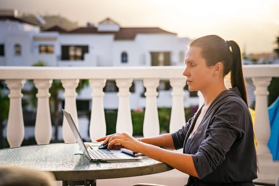 Woman Working on Laptop Sitting on Balcony